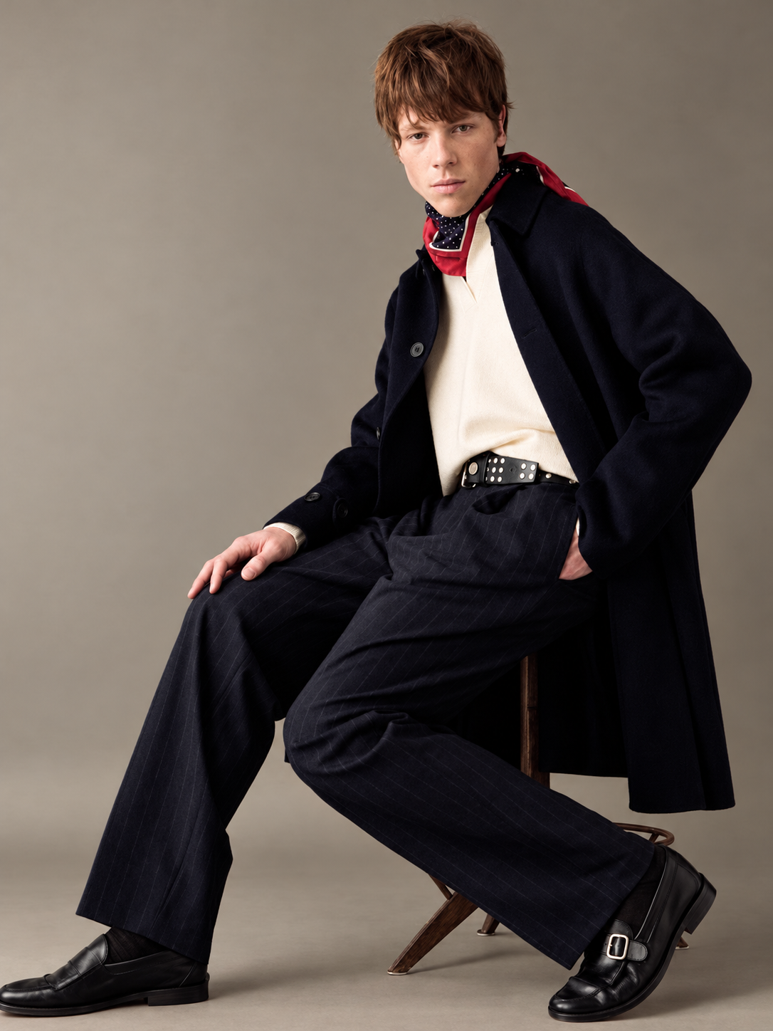 Look uomo con cappotto blu, maglia avorio e foulard rosso